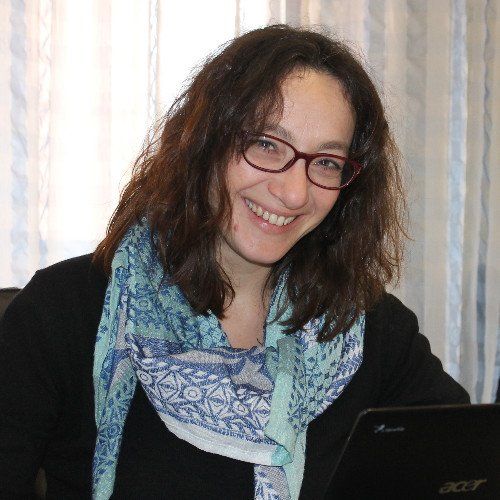Una donna che indossa occhiali e una sciarpa sorride davanti a un portatile Acer