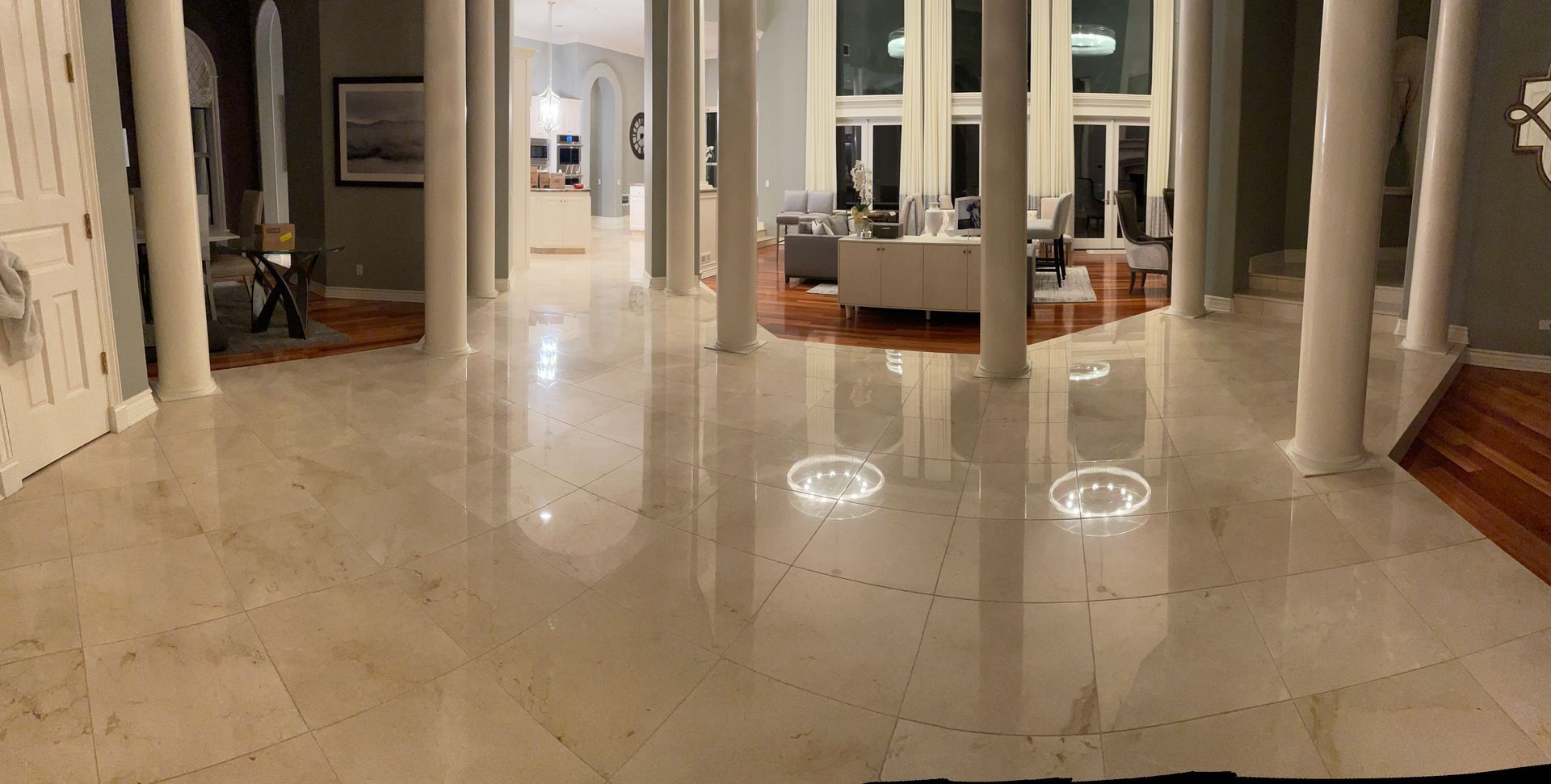 Spacious interior with marble floor, white columns, and a view into another room.