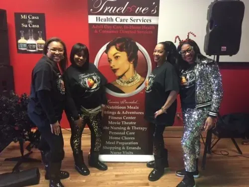 Five women posing beside a Trust One Health Care Services banner on a red-carpet event floor