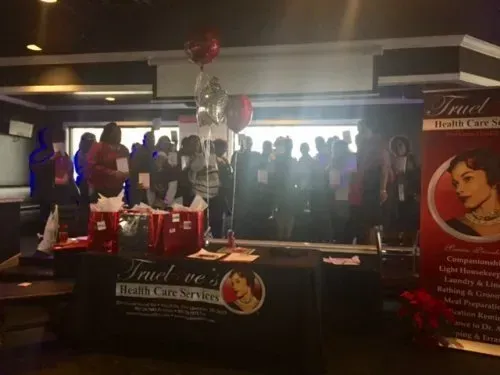 Trade show booth with cocktail table, red cups, and a crowd of people in the background.