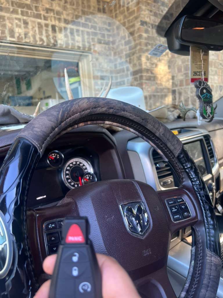 Dodge Ram steering wheel and dashboard with a key fob, viewed from the driver’s seat in a garage