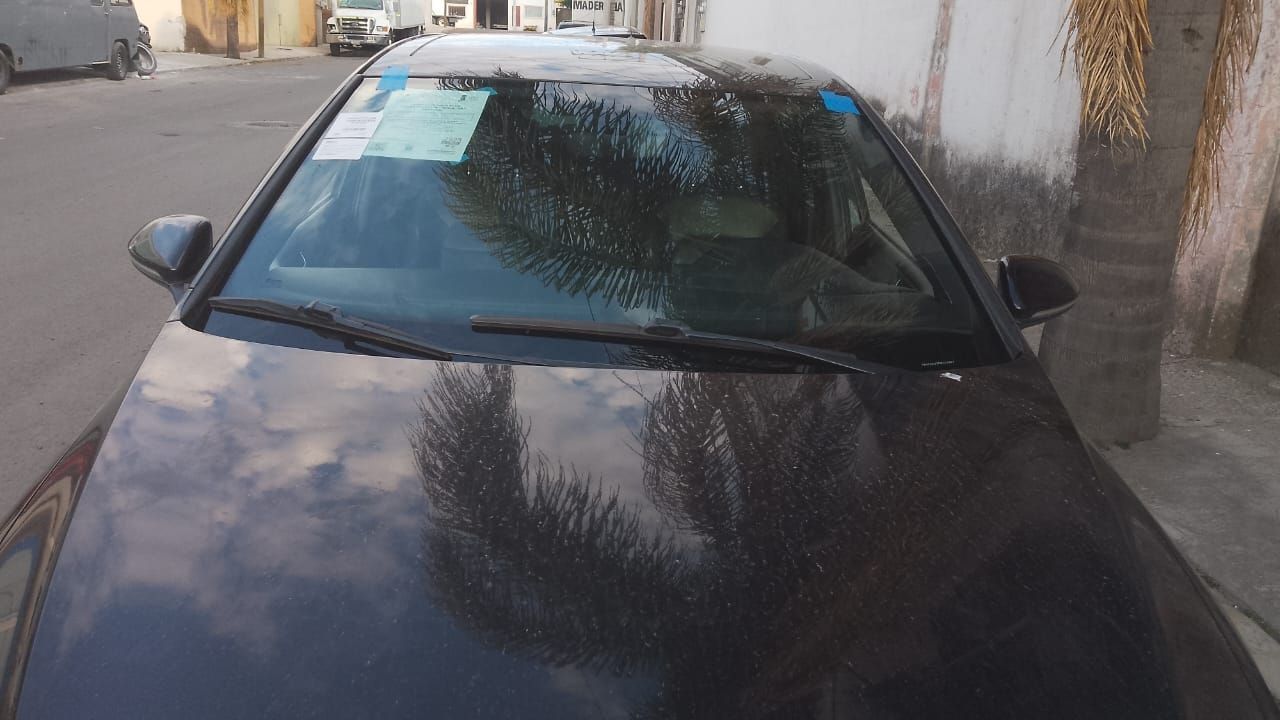 Un coche negro está aparcado al costado de la carretera frente a un edificio.
