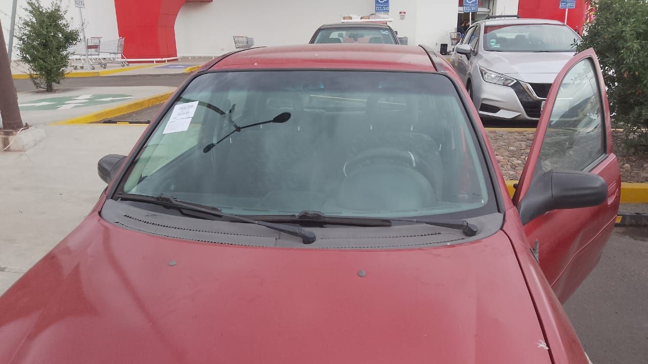 Un coche rojo está aparcado en un estacionamiento con la puerta abierta.