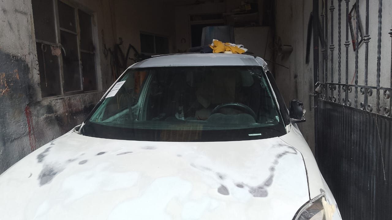 Un coche blanco está aparcado en un garaje al lado de un edificio.