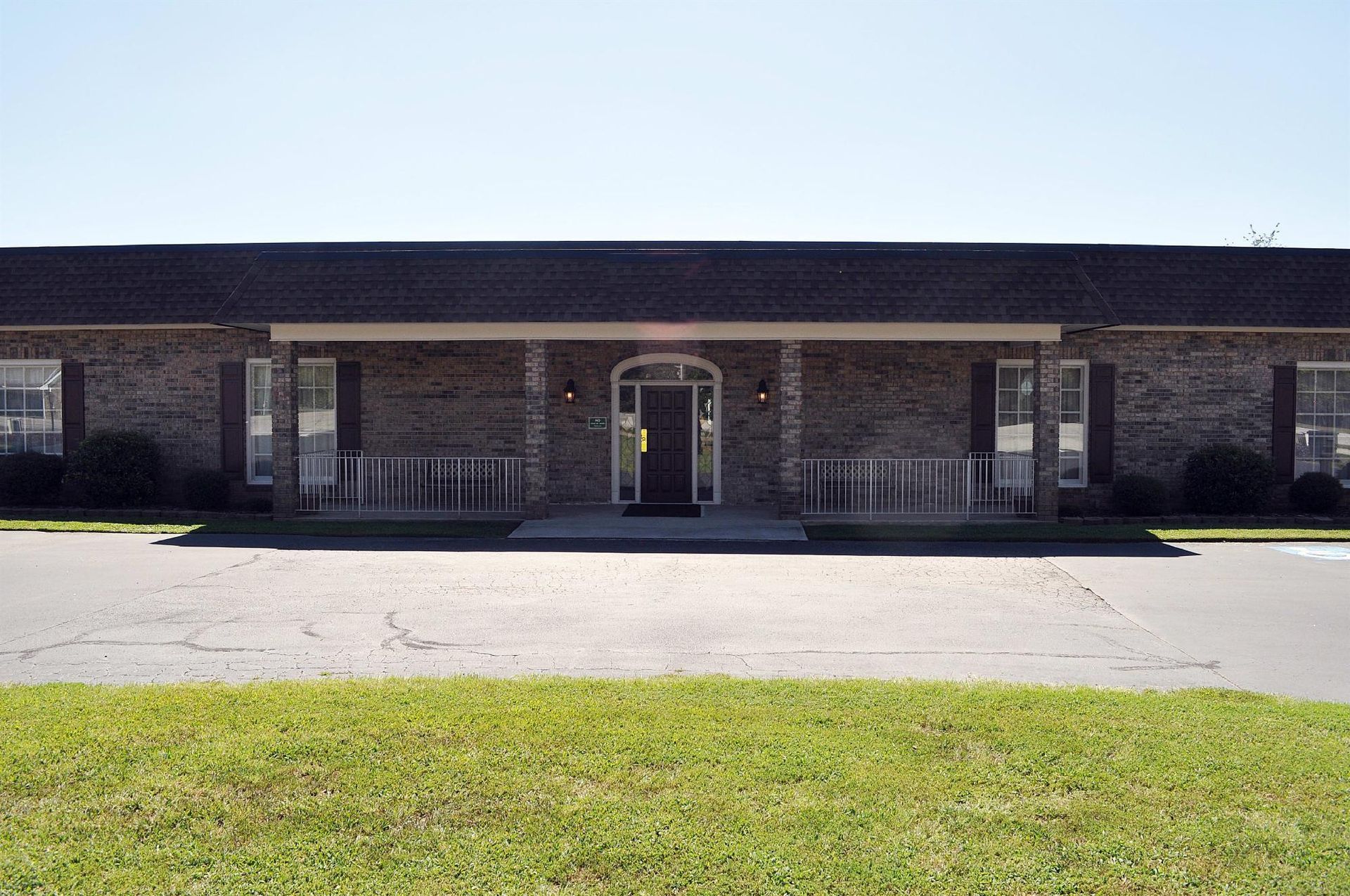 Brick building with covered entrance, accessible ramp, and a paved driveway in front.