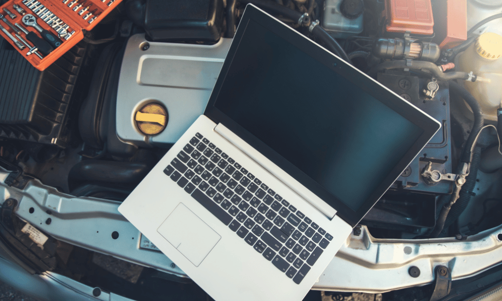 Laptop computer connected to vehicle for diagnostic testing under hood