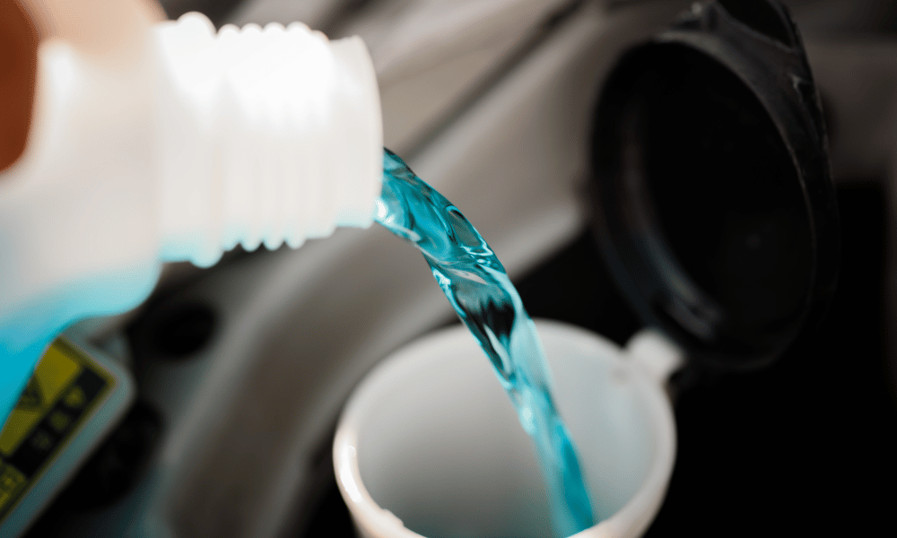 Technician pouring windshield washer fluid into vehicle reservoir
