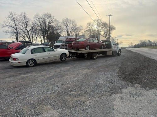 Null's Towing flatbed trailer with a red vehicle on top and white vehicle behind