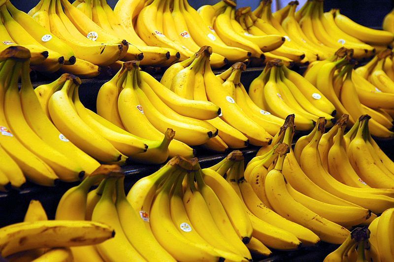 Een stapel rijpe gele bananen bij een marktkraam.
