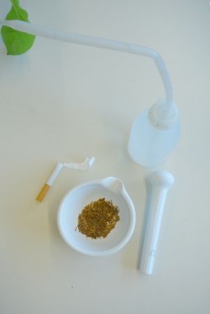 Een witte bloem met een gebogen steel in een vaasje, naast een schaaltje met gouden glitter en een