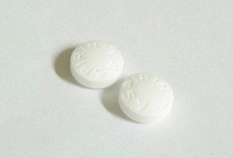 Twee witte ronde tabletten op een lichtgrijze ondergrond.
