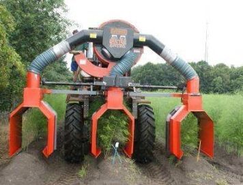Rode landbouwmachine met grote banden en oranje klauwen in een veld, van voren gezien.