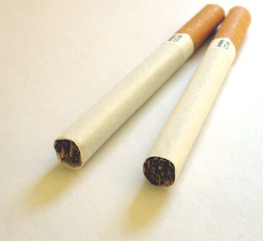 Twee sigaretten liggen op een licht oppervlak, één gedeeltelijk opgerookt en één onaangestoken.