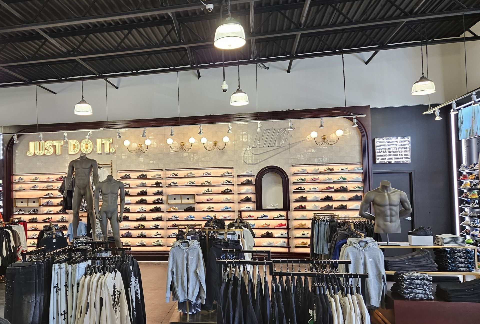 Clothing store interior with jeans, shirts, and jackets displayed on racks and wall shelves under bright lights