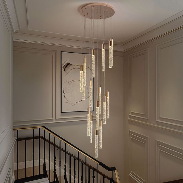 Elegant stairwell with beige paneled walls, black railing, and a modern hanging chandelier.