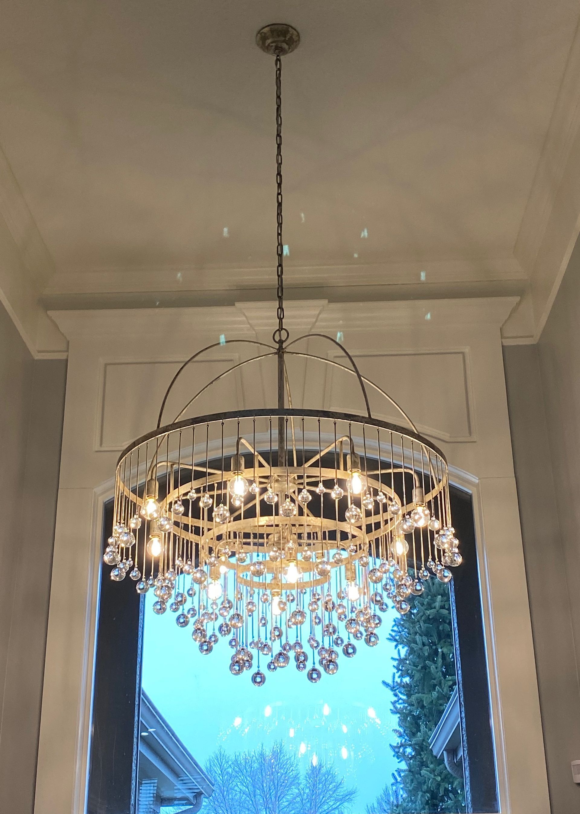 Ornate gold chandelier hanging from a ceiling above a bright window