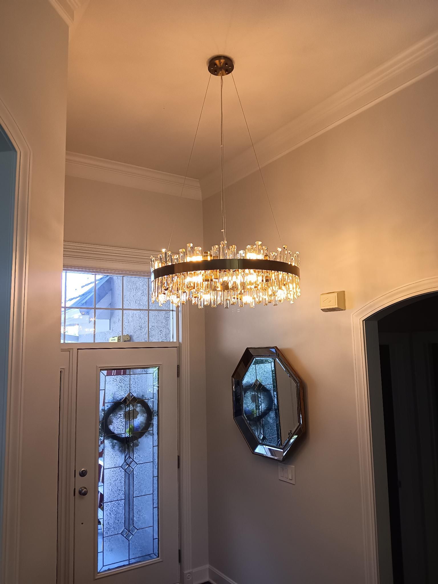 Entryway with a chandelier, front door, mirror, and frosted glass window in a beige foyer