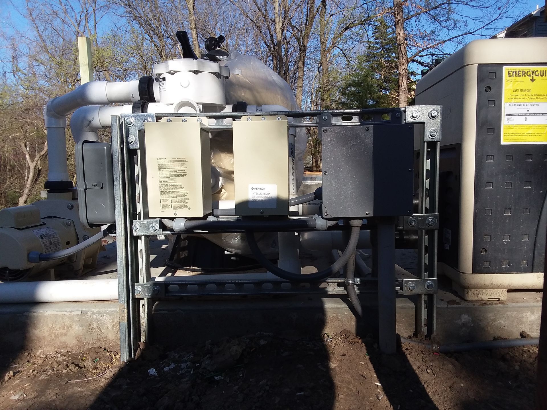 Industrial water treatment tank with piping and control panels outdoors, showing a metal filtration unit in a yard