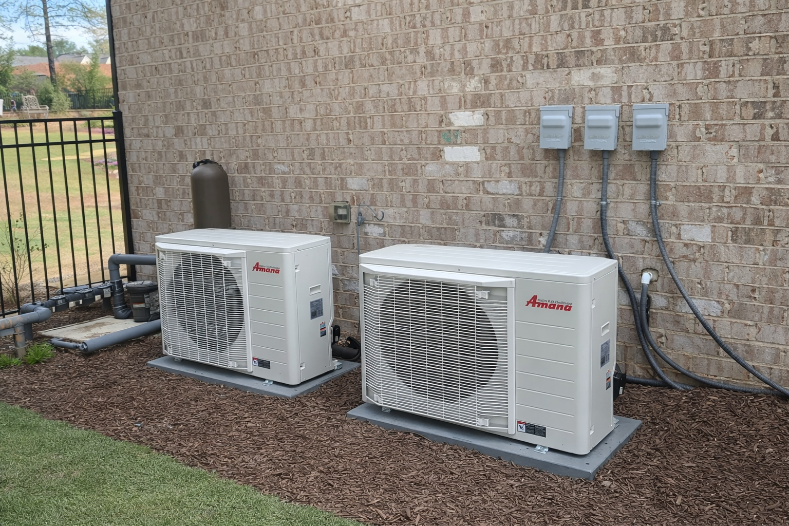 Two Amana hvac units outside of a large brick house where they were recently installed after the hvac units needed replaced