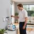 man adjusting ac heating and cooling system in a customer's house while wearing a white uniform