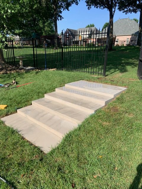 A set of concrete steps sitting on top of a lush green lawn.