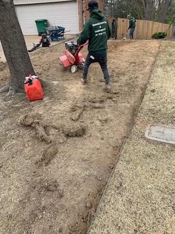 A man is using a lawn mower to remove dirt from a yard.