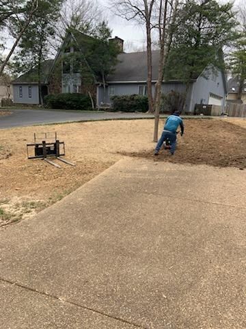 A man is kneeling down in the dirt in front of a house.