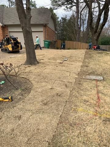 A man is standing in the grass in front of a house.
