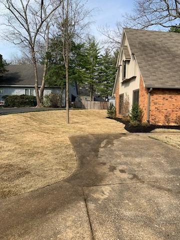 A house with a large driveway and a large lawn in front of it.