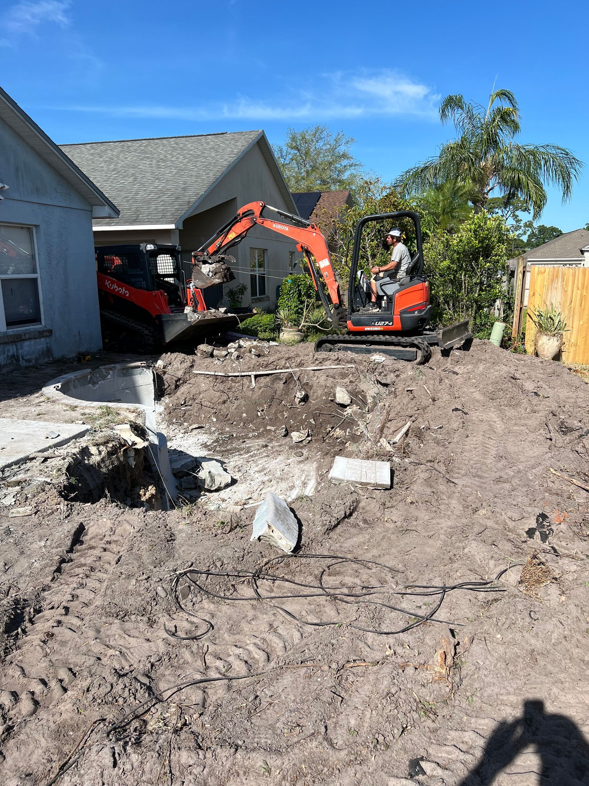 a yellow excavator is pouring gravel into a hole in the ground .