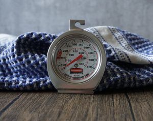 Round metal timer on a wooden table in front of a blue-and-white checkered cloth.