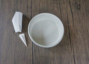 Broken white ceramic bowl and two shards on a wooden surface