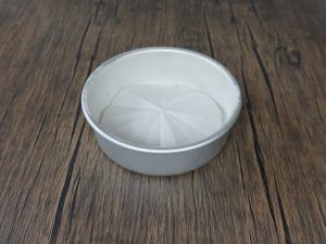 White ceramic bowl on a wooden table with a clear liquid inside