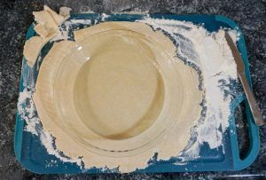 Beige plate on a blue tray, covered with white batter or cream spilled around it.