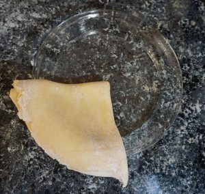 A pale pastry triangle on a clear glass plate on a dark speckled countertop.