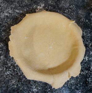 Round beige pastry or dough on a dark stone surface