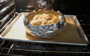 Pie baking in a foil-lined pan inside an oven