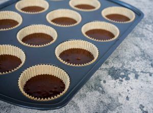 Chocolate cupcakes in a blue muffin tin with paper liners, ready to bake