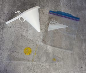 White plastic funnel and clear zip-top bags on a gray surface