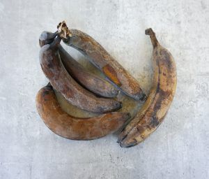 A bunch of ripe, brown bananas on a light gray background