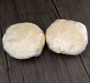 Two wrapped dough balls on a dark wooden surface