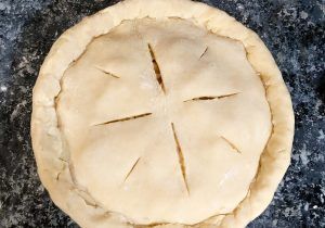 Top view of a round pastry with a star-shaped cut pattern on a dark surface