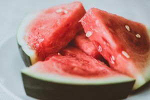 Sliced watermelon pieces with red flesh and dark green rind on a white plate