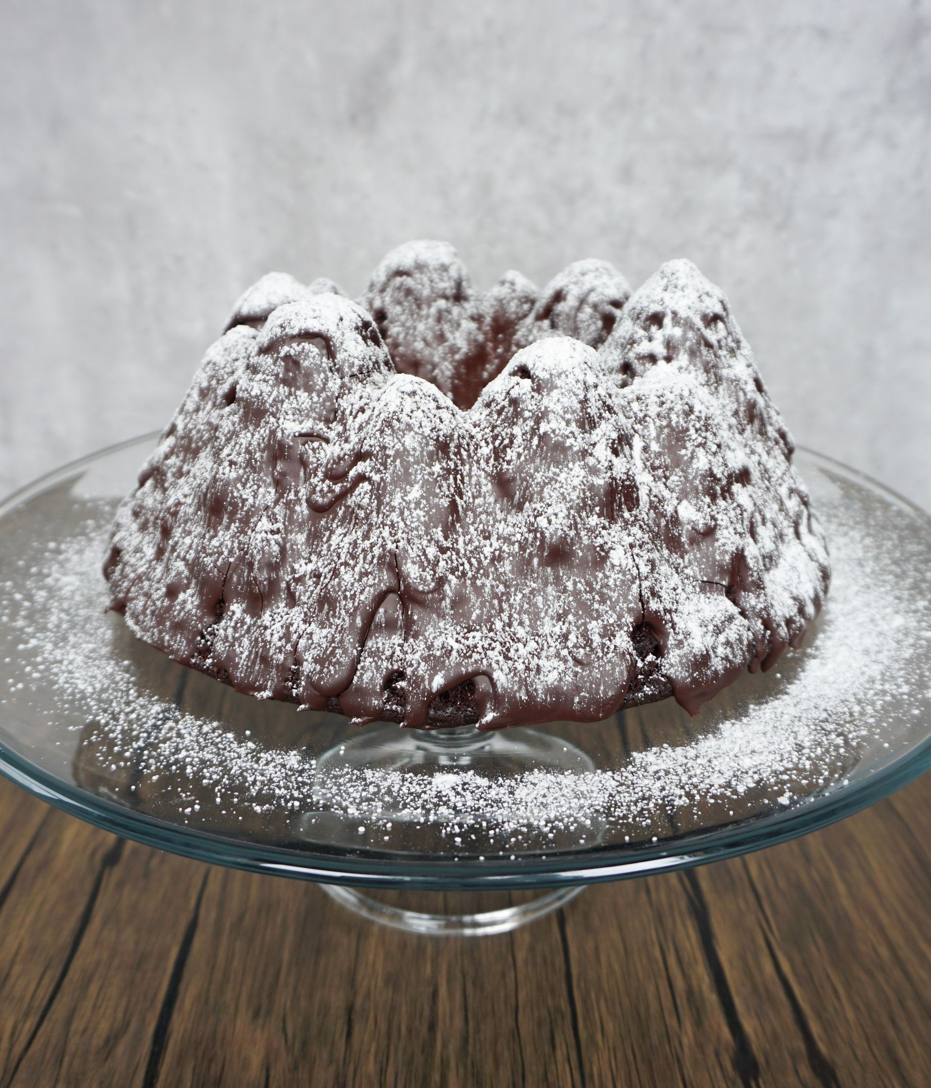 Powdered sugar-coated bundt cake on a glass pedestal stand