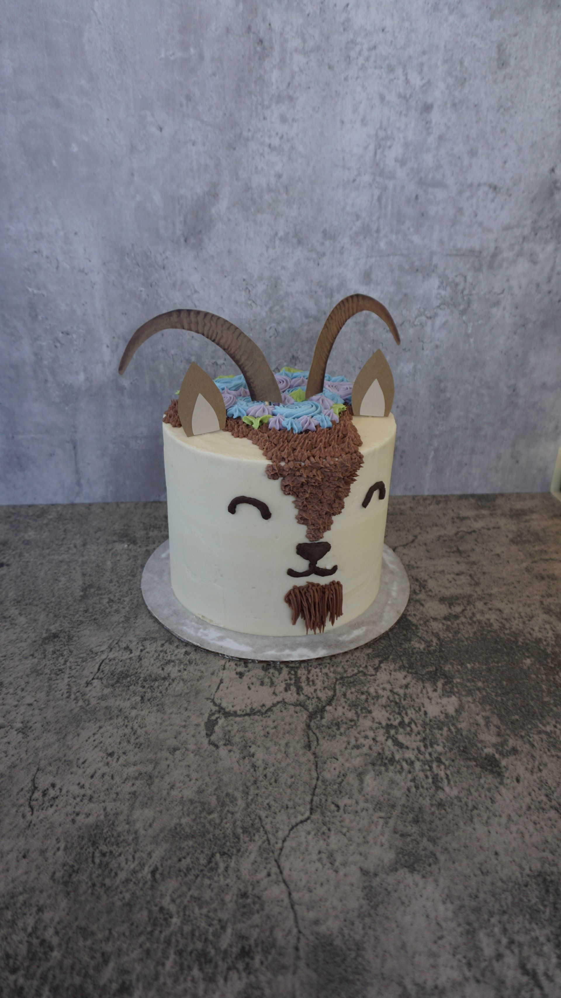 Decorated white cake with antlers and floral accents on a gray tabletop