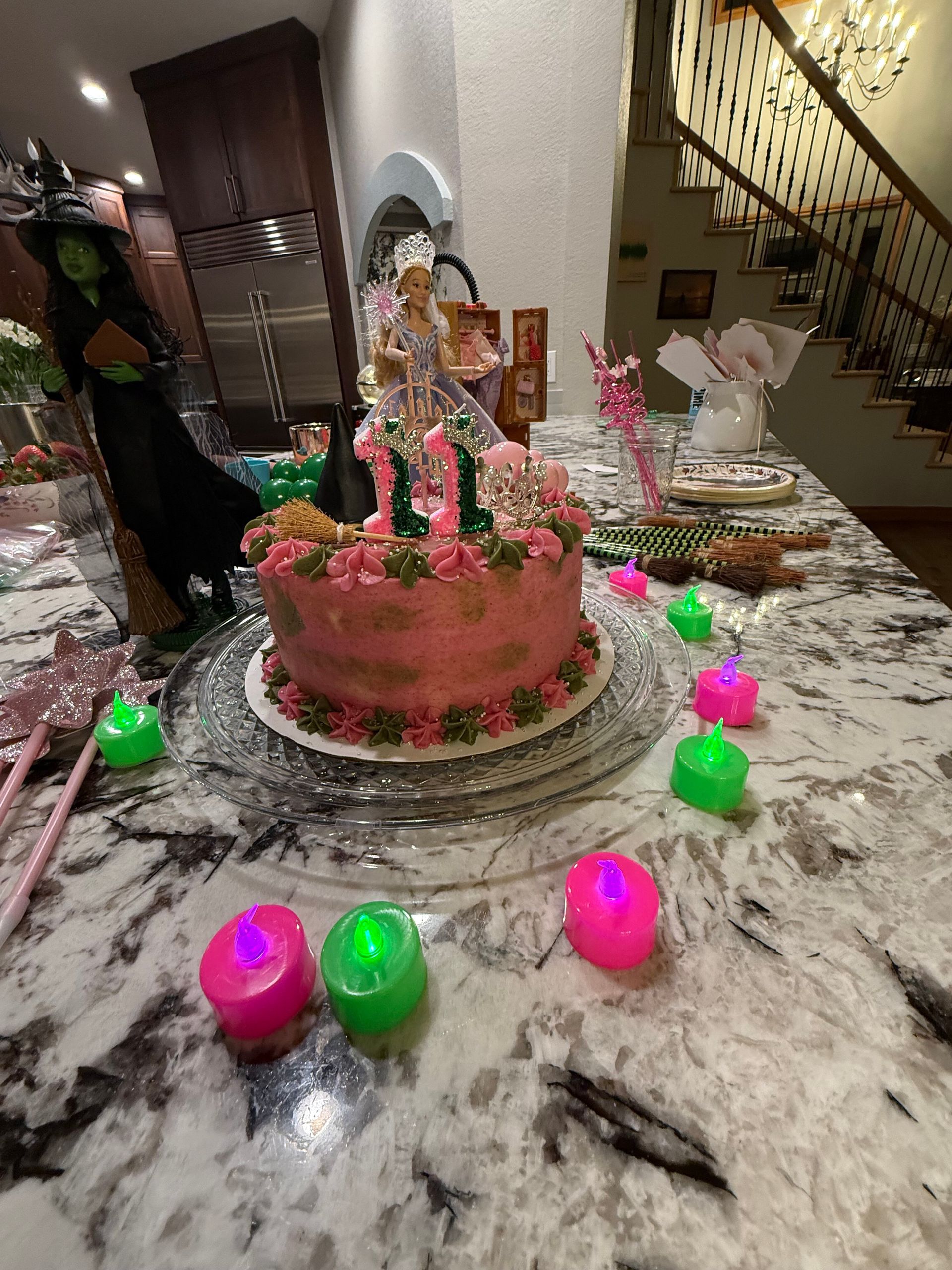 Birthday cake on a marble table with colorful glowing candles and party decorations indoors