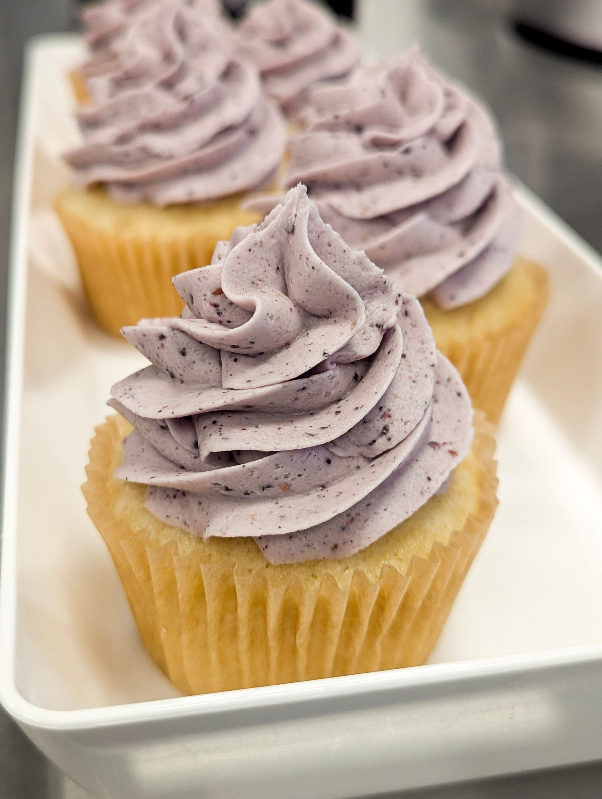 Lavender-frosted cupcakes on a white tray