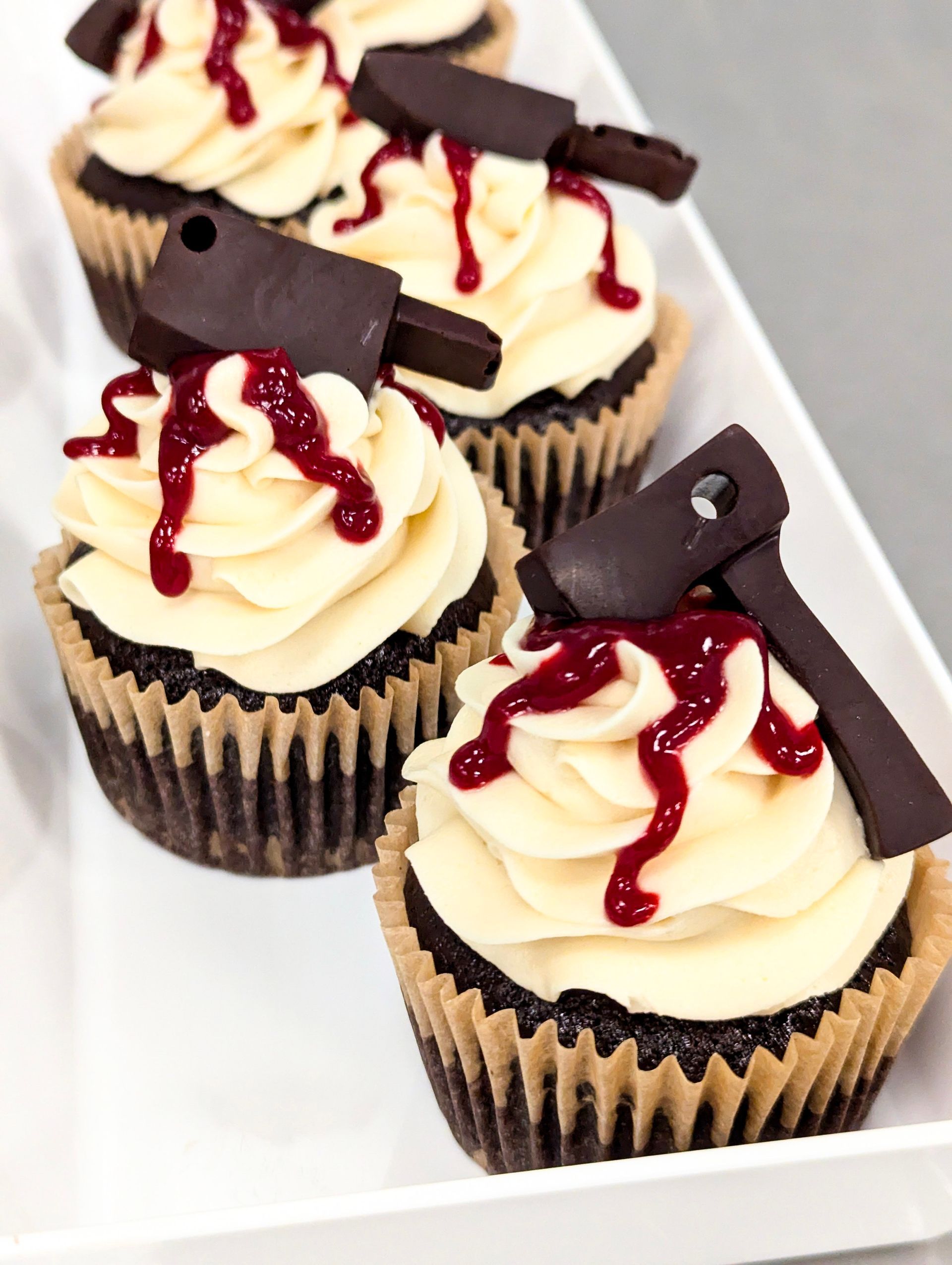 Assorted frosted cupcakes with sprinkles and swirled toppings in various colors, arranged closely together