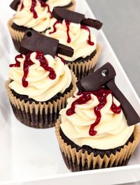 Assorted frosted cupcakes with sprinkles and swirled toppings in various colors, arranged closely together