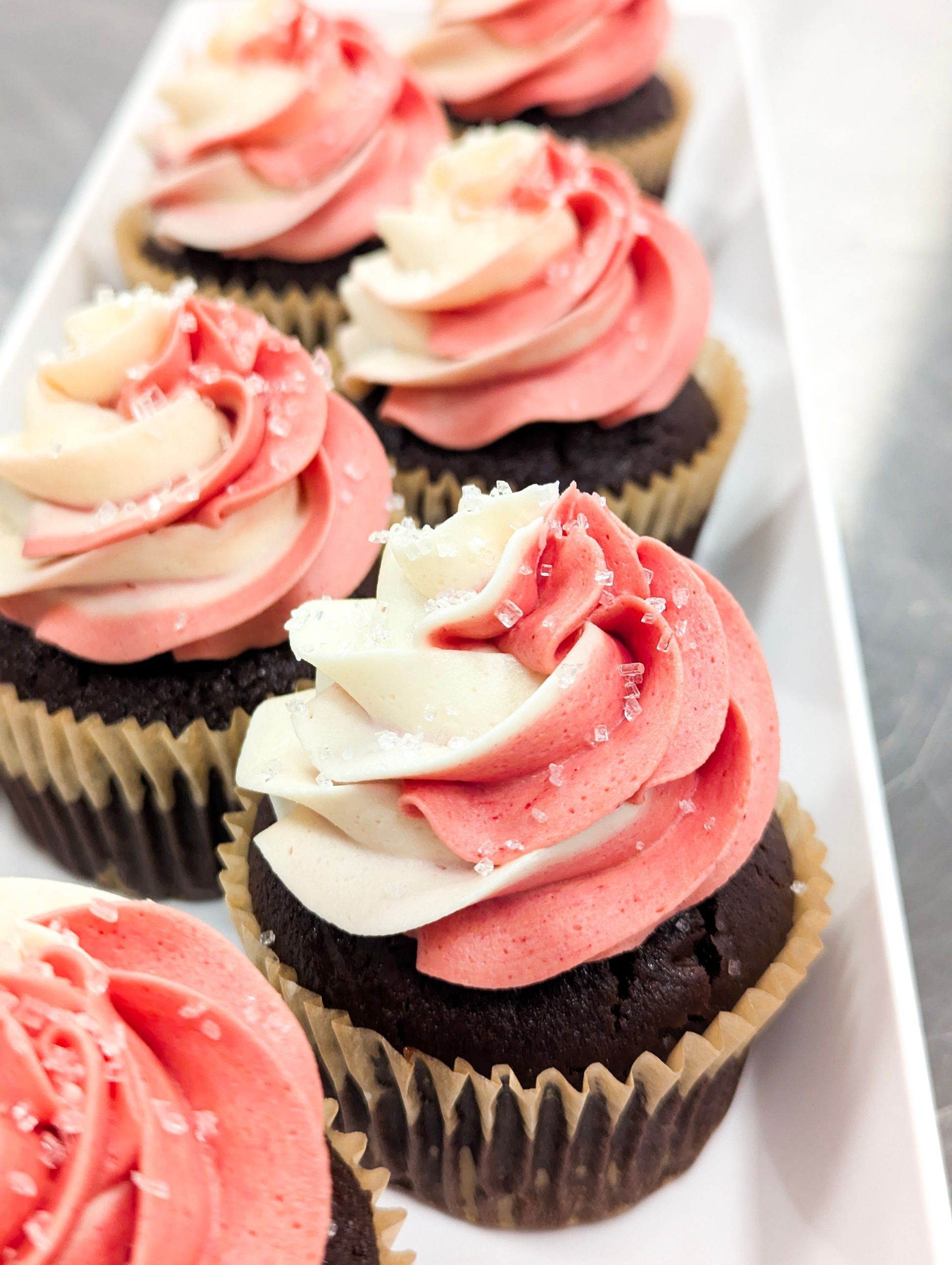 Pink and white swirled cupcakes in a white box